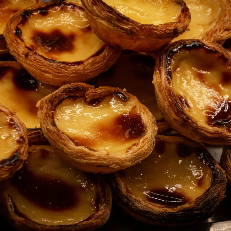 A tempting display of traditional Portuguese Pastel de Nata pastries, glistening with caramelized tops.