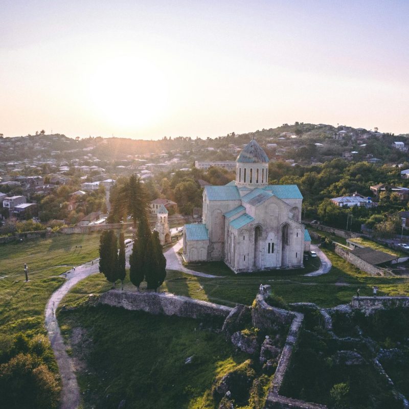 Aerial view of Bagrati Cathedral in Kutaisi, Georgia, showcasing stunning landscape at sunrise.